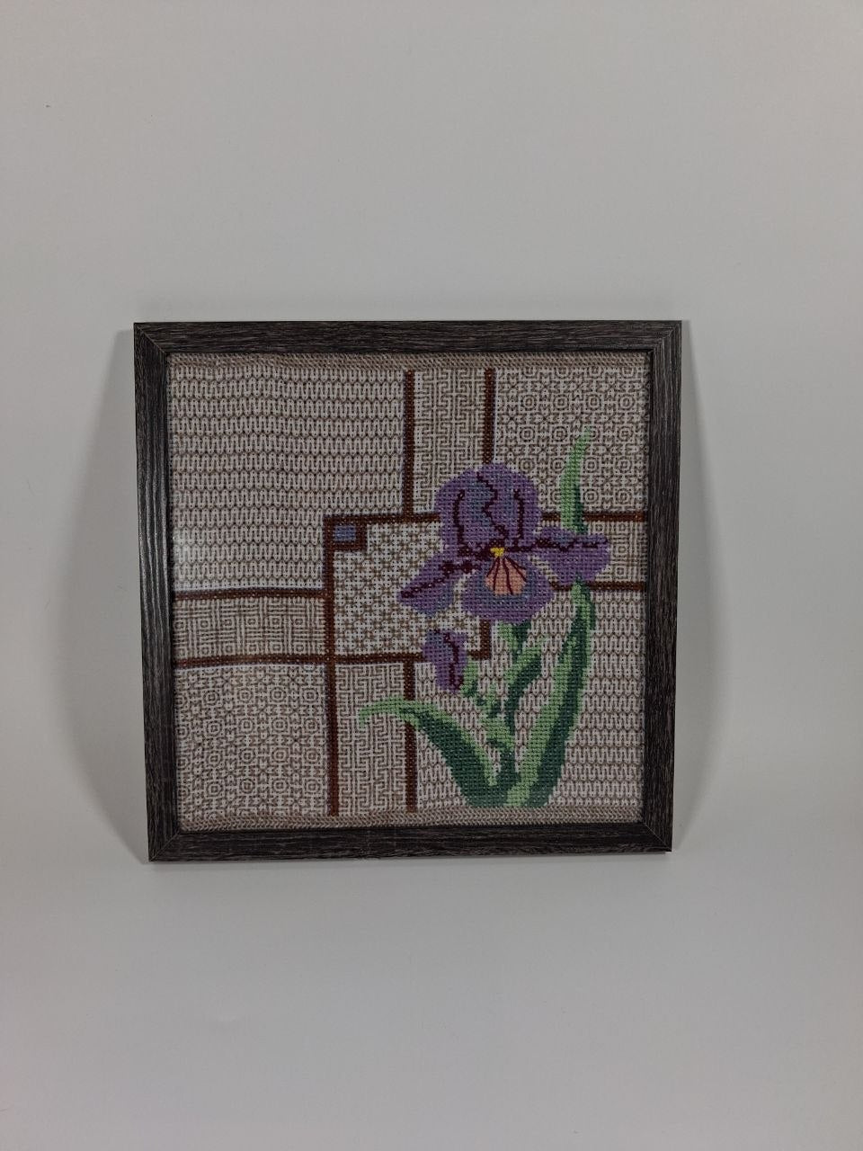 Hand-embroidered purple iris on patterned cotton canvas in a dark wooden frame